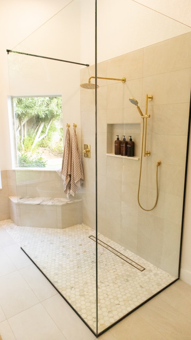 Modern shower with frameless glass and gold fixtures after Houston shower replacement