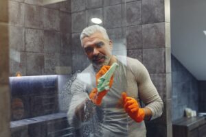 man using microfiber cloth to clean Houston shower glass door